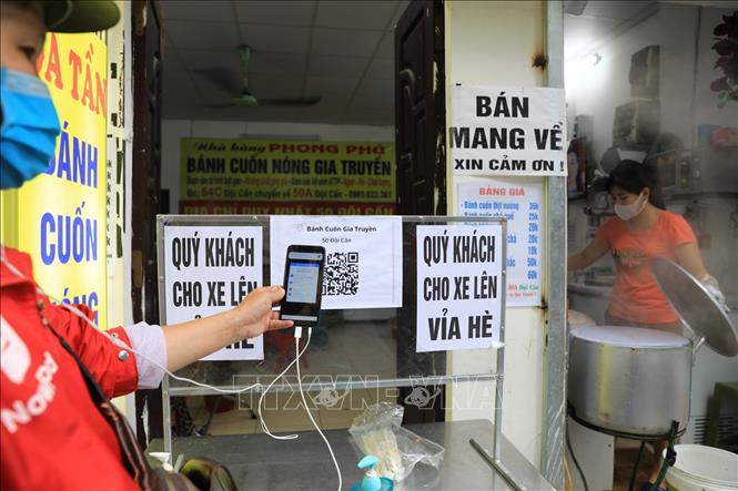 Tại một cửa hàng bán bánh cuốn trên phố Đội Cấn, các shipper đến lấy hàng phải quét mã QR-code để khai báo y tế rồi mới được lấy hàng. Ảnh: Thành Đạt - TTXVN 
