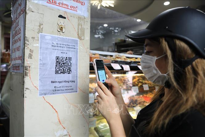 Khách sẽ được các chủ cửa hàng yêu cầu quét mã QR trước khi mua hàng. Ảnh: Thành Đạt - TTXVN 