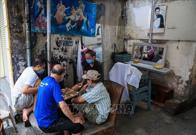 Trong ảnh: Các cụ già đeo khẩu trang đánh cờ đầu con ngõ nhỏ trên đường Bạch Đằng. Ảnh: Thành Đạt - TTXVN