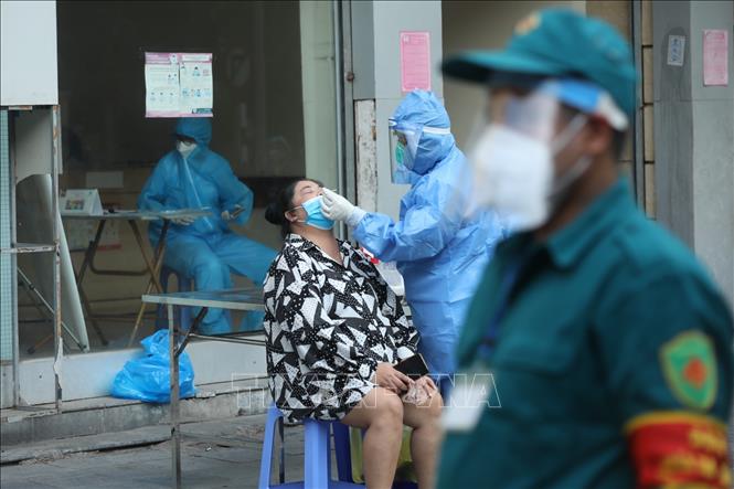 Trong ảnh: Nhân viên y tế lấy mẫu cho người dân bên ngoài cổng Bệnh viện Việt Đức. Ảnh: Minh Quyết - TTXVN