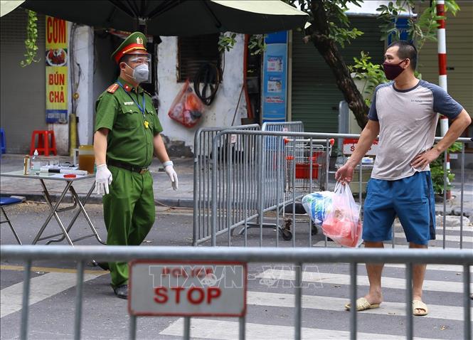 Trong ảnh: Công an hướng dẫn người dân đưa đồ tiếp tế cho người thân trong Bệnh viện hữu nghị Việt Đức qua cổng đường Tràng Thi. Ảnh: Hoàng Hiếu - TTXVN 