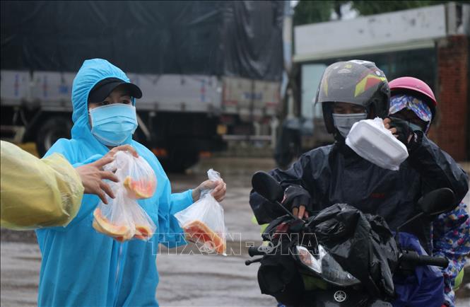 Người dân Phú Yên đội mưa hỗ trợ phần cơm miễn phí tiếp sức cho người dân các tỉnh phía Nam về quê. Ảnh: Phạm Cường-TTXVN