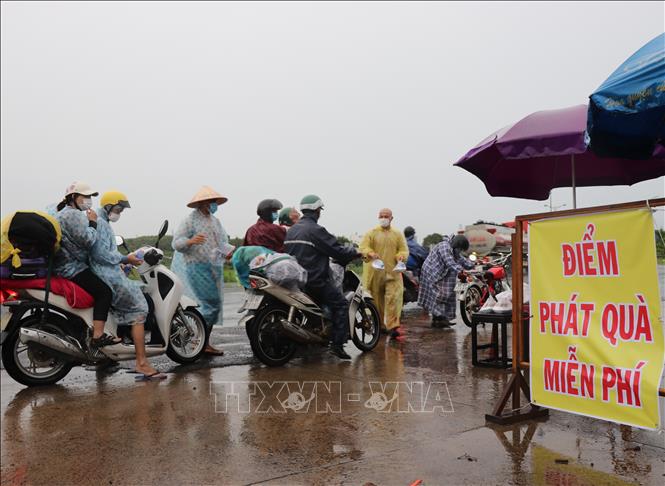 Người dân Phú Yên đội mưa hỗ trợ phần cơm miễn phí tiếp sức cho người dân các tỉnh phía Nam về quê. Ảnh: Phạm Cường-TTXVN