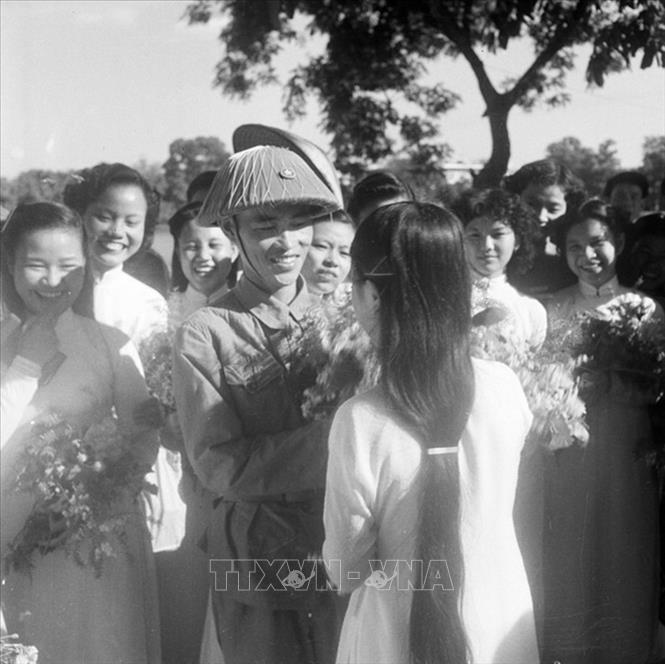 Thiếu tướng Vương Thừa Vũ, Tư lệnh Đại đoàn 308, Chủ tịch Ủy ban Quân chính Thành phố giữa vòng vây của các nữ sinh trường Trưng Vương tặng hoa chúc mừng bên hồ Hoàn Kiếm trong ngày giải phóng Thủ đô. Ảnh: Tư liệu TTXVN