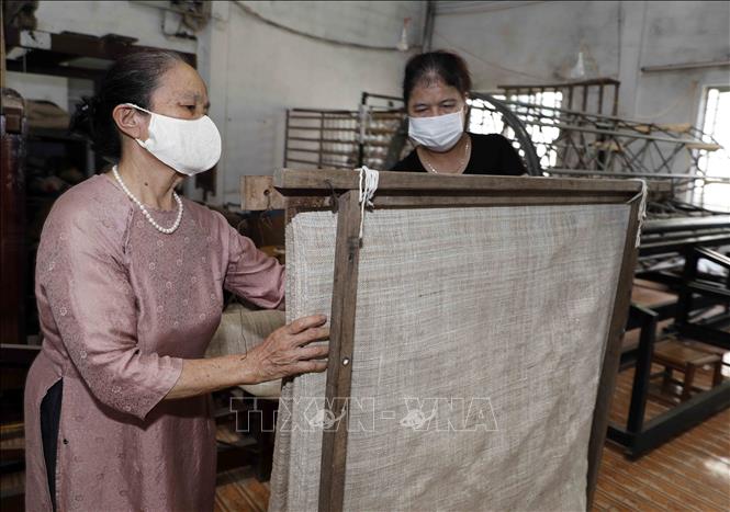 Ngoài việc quản lý, bà Phan Thị Thuận thường xuyên kiểm tra, hướng dẫn người lao động ở xưởng dệt. Ảnh: Trần Việt - TTXVN