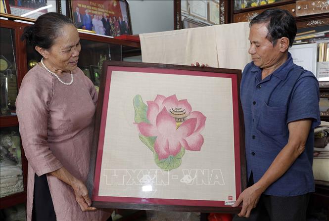 Bà Phan Thị Thuận tâm đắc với sản phẩm dệt từ sợi tơ sen. Ảnh: Trần Việt - TTXVN