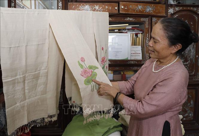 Bà Phan Thị Thuận tâm đắc với sản phẩm dệt từ sợi tơ sen. Ảnh: Trần Việt - TTXVN