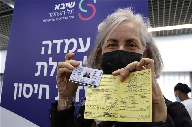 Trong ảnh: Một người Israel giới thiệu thẻ quốc tế và giấy Chứng nhận tiêm vaccine ngừa COVID-19 tại trung tâm y tế Sheba ở Ramat Gan, gần Tel Aviv, ngày 14/1/2021. Ảnh: AFP/TTXVN  