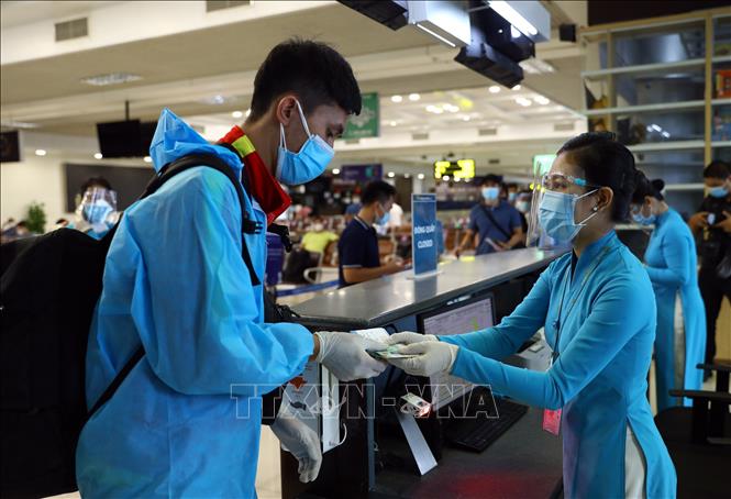 Nhiều hành khách tự trang bị quần áo bảo hộ phòng, chống dịch COVID-19 khi lên máy bay. Ảnh: Huy Hùng – TTXVN