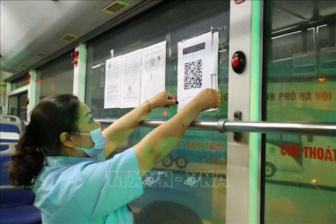 Trong ảnh: Phụ xe Nguyễn Ngọc Hường (xe 100 tuyến Đặng Xá - Long Biên) dán mã QR tại bến để hành khách thực hiện khai báo y tế. Ảnh: Hoàng Hiếu - TTXVN 
