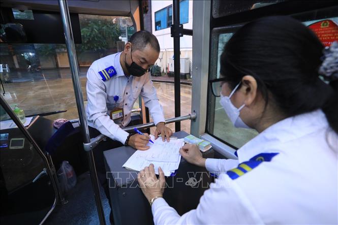 Trong ảnh: Lái xe Hoàng Quốc Bảo và nhân viên bán vé tuyến xe buýt BRT 01 Kim Mã - Yên Nghĩa ký lệnh điều động xe xuất bến Kim Mã. Ảnh: Tuấn Anh - TTXVN