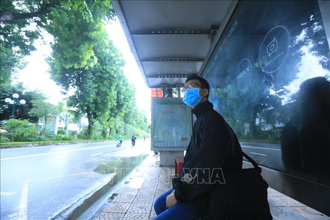 Trong ảnh: Anh Vũ Duy Khánh chờ xe buýt tuyến 18 tại trạm đón, trả khách trên phố Giảng Võ. Ảnh: Tuấn Anh - TTXVN