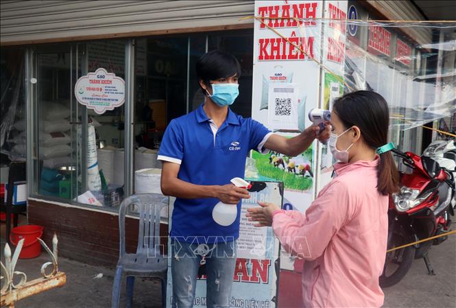 Trong ảnh: Đo thân nhiệt, sát khuẩn cho người dân đi mua hàng hóa tại chợ Vĩnh Bảo, thành phố Rạch Giá (Kiên Giang). Ảnh: Lê Huy Hải - TTXVN