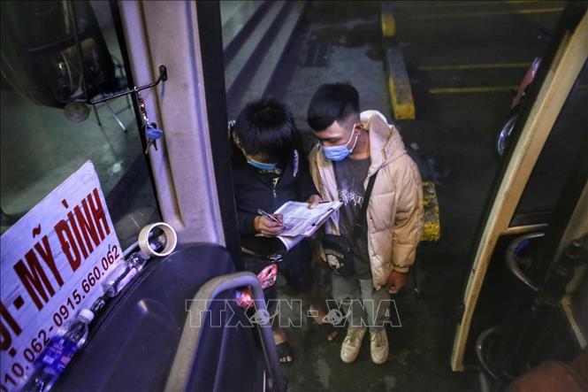 Phụ xe kiểm tra thông tin từng hành khách trước khi lên xe. Ảnh: Tuấn Đức - TTXVN