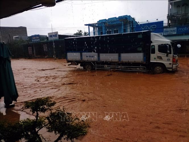 Trong ảnh: Các xe tải lớn chạy qua làm nước tràn vào nhà dân. Ảnh: TTXVN phát