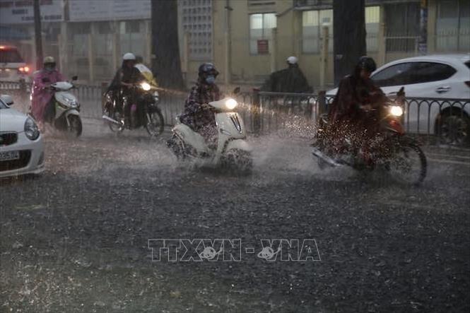 Người dân điều khiển phương tiện trong cơn mưa mịt mù trên đường Hồ Học Lãm (quận Bình Tân). Ảnh: Hồng Giang - TTXVN