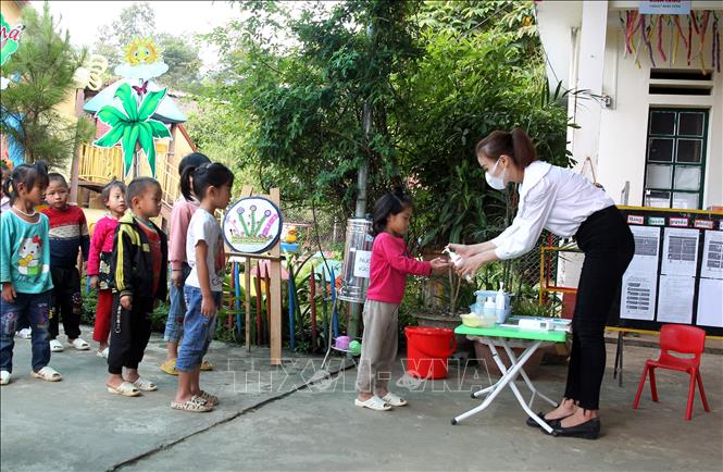 Trong ảnh: Các học sinh được cô giáo đo thân nhiệt, rửa tay sát khuẩn trước khi vào lớp học. Ảnh: Quốc Khánh - TTXVN