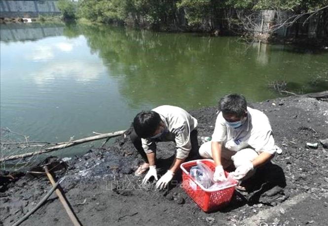 Trong ảnh: Lực lượng chức năng lấy mẫu chất thải để điều tra. Ảnh: TTXVN phát