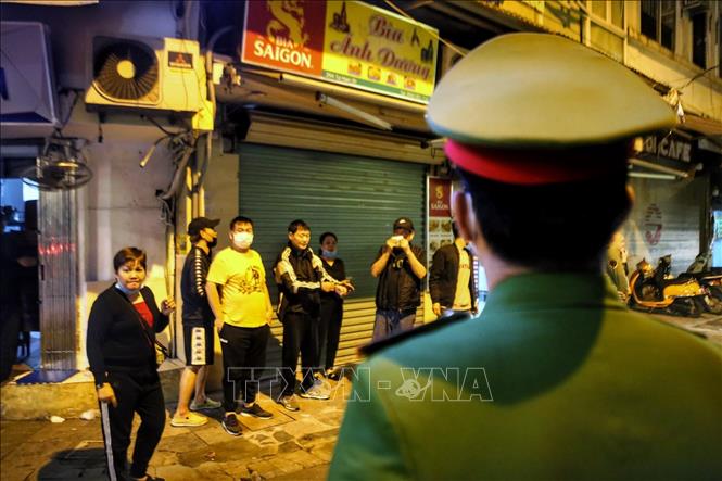 Lực lượng công an phường đi kiểm tra, nhắc nhở các hàng quán tại phố Tạ Hiện, quận Hoàn Kiếm thực hiện nghiêm việc đóng cửa sau 21 giờ. Ảnh: Tuấn Đức - TTXVN