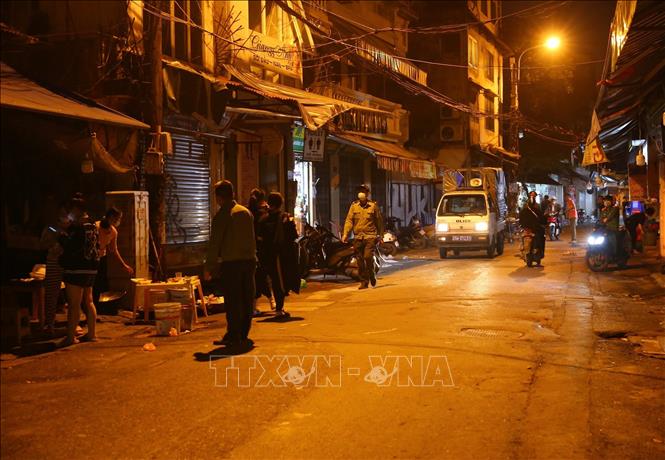 Lực lượng chức năng phường Hàng Bồ (quận Hoàn Kiếm) nhắc nhở các hộ kinh doanh đóng cửa đúng giờ theo quy định. Ảnh: Hoàng Hiếu - TTXVN 