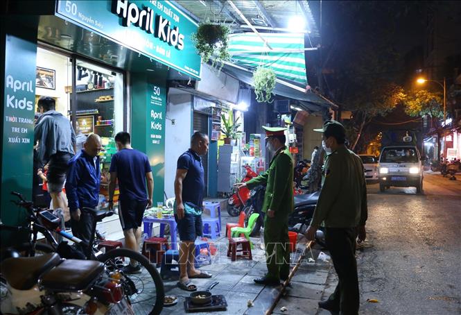 Lực lượng chức năng phường Hàng Bồ (quận Hoàn Kiếm) nhắc nhở các hộ kinh doanh đóng cửa đúng 21 giờ. Ảnh: Hoàng Hiếu - TTXVN 