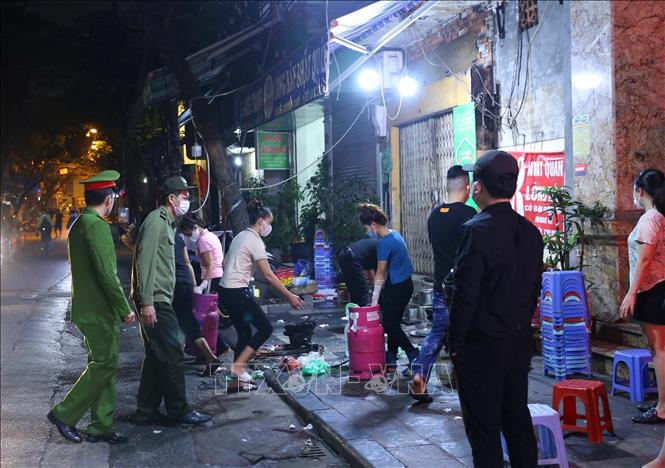 Lực lượng chức năng phường Hàng Bồ (quận Hoàn Kiếm) nhắc nhở các hộ kinh doanh ăn uống đóng cửa đúng 21 giờ. Ảnh: Hoàng Hiếu - TTXVN 