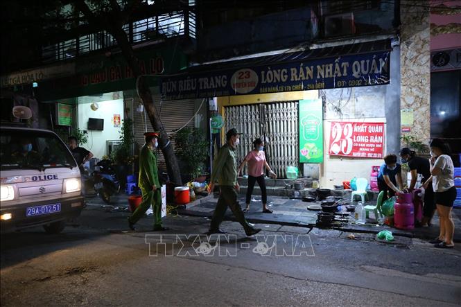 Lực lượng chức năng phường Hàng Bồ (quận Hoàn Kiếm) nhắc nhở các hộ kinh doanh ăn uống trên địa bàn đóng cửa đúng 21 giờ. Ảnh: Hoàng Hiếu - TTXVN 