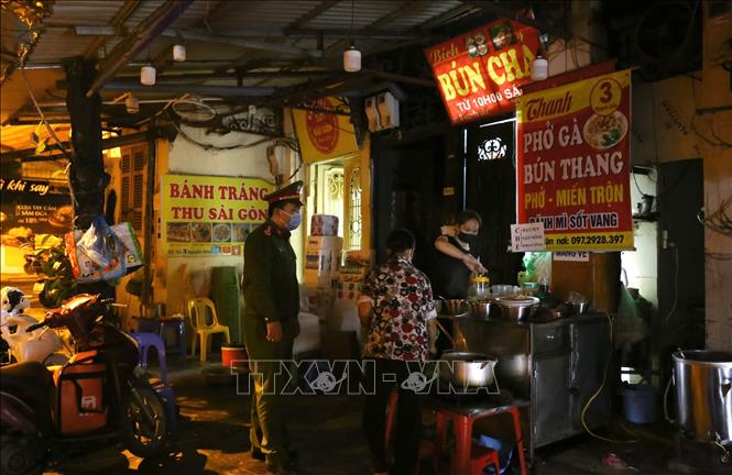 Lực lượng chức năng phường Hàng Bồ (quận Hoàn Kiếm) nhắc nhở các hộ kinh doanh đóng cửa đúng giờ theo quy định. Ảnh: Hoàng Hiếu - TTXVN 