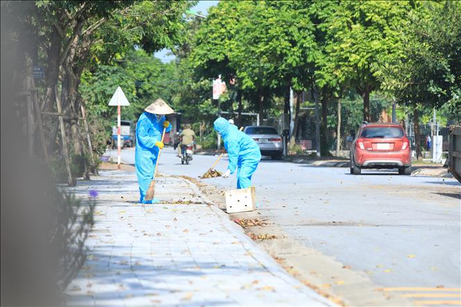 Trong ảnh: Nhân viên vệ sinh mặc đồ bảo hộ khi dọn rác trong khu vực phong tỏa đảm bảo phòng, chống dịch. Ảnh: Tuấn Anh - TTXVN