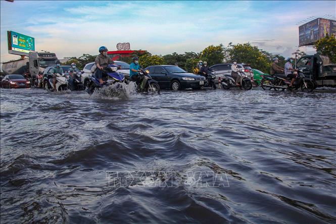 Triều cường gây ngập các tuyến đường ảnh hưởng đến việc đi lại của người dân. Ảnh: Thanh Liêm - TTXVN