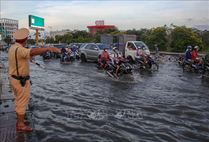 Cảnh sát giao thông hướng dẫn người dân đi qua điểm ngập gần nút giao IC3 (quận Cái Răng, TP Cần Thơ). Ảnh: Thanh Liêm - TTXVN