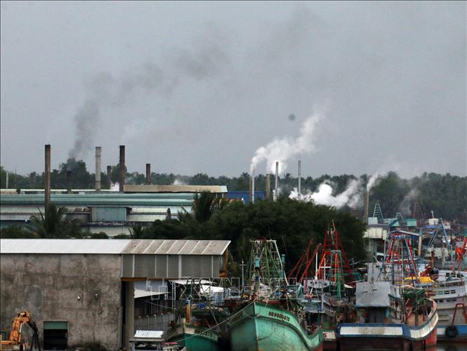 Trong ảnh: Khói thải mù mịt xả ra từ các nhà máy bột cá nằm dọc sông Cái Bé. Ảnh: Lê Sen - TTXVN
