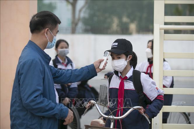 Trong ảnh: Đo thân nhiệt cho học sinh trước khi vào lớp học ở trường THCS Quán Bàu, thành phố Vinh. Ảnh: TTXVN