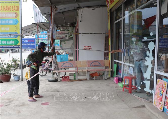 Trong ảnh: Tại khu vực ngoài chợ Bản Phủ, không thuộc phạm vi kiểm soát, người mua hàng và chủ cửa hàng giao dịch khá thận trọng theo một cách anh toàn. Ảnh: Xuân Tiến – TTXVN 