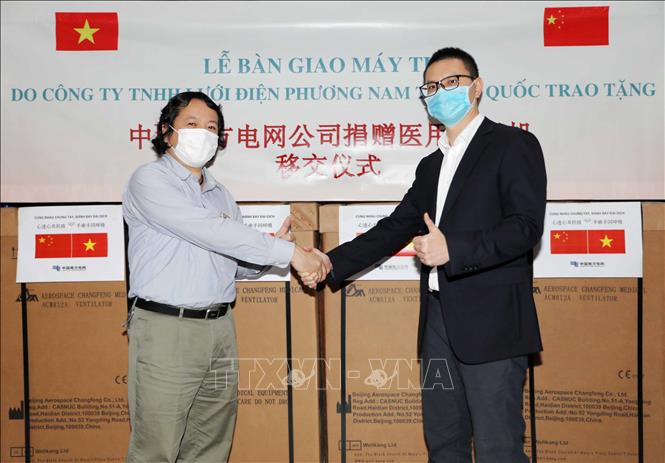 Trong ảnh: Ông Lian Zichuan (bên phải), Phó Trưởng đại diện, Văn phòng đại diện Công ty TNHH Lưới điện Phương Nam Trung Quốc (CSG) tại Việt Nam bàn giao máy thở cho Ông Nguyễn Quang, Trưởng phòng Vật tư Trang thiết bị, Viện Vệ sinh Dịch tễ Trung ương (Bộ Y tế). Ảnh: Thanh Tùng - TTXVN 