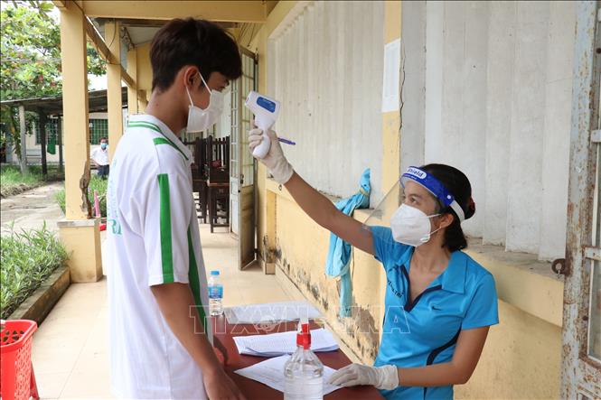 Các học sinh tại Trung tâm giáo dục thường xuyên và nghề nghiệp Ba Tri, huyện Ba Tri, tỉnh Bến Tre được khám sàng lọc, đo nhiệt độ trước khi tiêm vaccine phòng COVID-19. Ảnh: Chương Đài - TTXVN