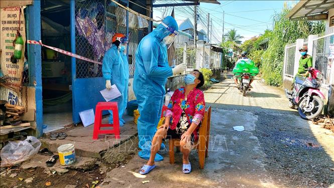 Trong ảnh: Chị Huỳnh Ngọc Trang, Tổ y tế cộng đồng phường Phước Thới, quận Ô Môn và sinh viên Trường ĐHYD Cần Thơ Trần Ngô Quang, Đội Y tế lưu động số 51 tham gia hỗ trợ phường Phước Thới lấy mẫu test định kỳ cho F1, F0 tại nhà. Ảnh: Thu Hiền - TTXVN