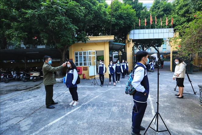 Trong ảnh: Học sinh lớp 12 trường THPT Phan Đình Phùng, quận Ba Đình được đo thân nhiệt trước khi vào trường. Ảnh: Tuấn Anh - TTXVN