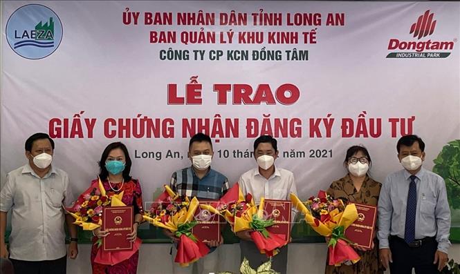 Lãnh đạo Sở Kế hoạc & Đầu tư tỉnh và Ban Quản lý khu kinh tế Long An trao giấy chứng nhận đăng ký cho các đầu tư. Ảnh: Thanh Bình-TTXVN