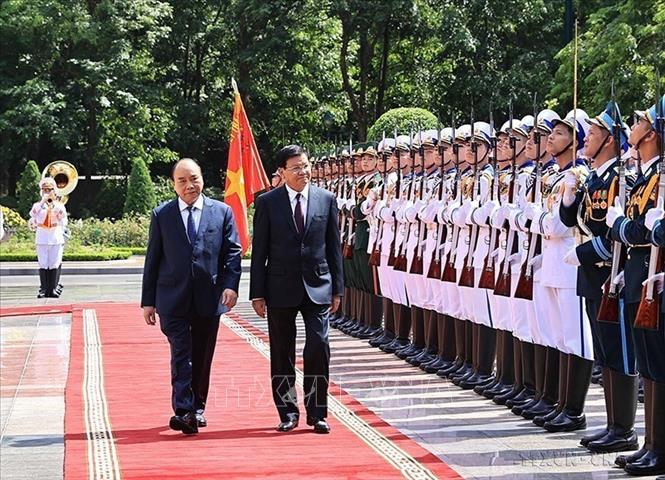 Photo: State President Nguyen Xuan Phuc and General Secretary of the Lao People's Revolutionary Party (LPRP) Central Committee and President of Laos Thongloun Sisoulith review the guards of honour during the latter's official friendship official visit to Vietnam, in Hanoi, on June 28, 2021. VNA Photo: Thống Nhất