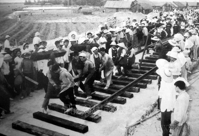 Trong kháng chiến chống Mỹ, cứu nước, ở khắp nơi trên toàn miền Bắc, nhân dân miền Bắcthực hiện mỗi người làm việc bằng hai, vừa củng cố, xây dựng cơ sở vật chất CNXH ở miền Bắc, vừa không ngừng đưa lực lượng, phương tiện và vật chất vào chiến trường miền Nam phát huy vai trò của hậu phương chiến lược, chi viện liên tục sức người, sức của cho chiến trường miền Nam. Trong ảnh: Đặt ray đường sắt tại ga Vinh ngày 25/4/1964. Ảnh: Tư liệu/TTXVN phát