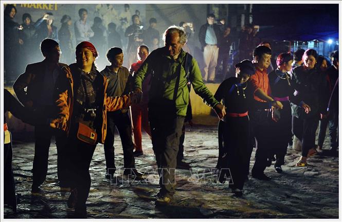 Photo: Foreign tourists join in a circle of Xoe dance in a Saturday practice at Bac Ha night market, Lao Cai province. VNA Photo