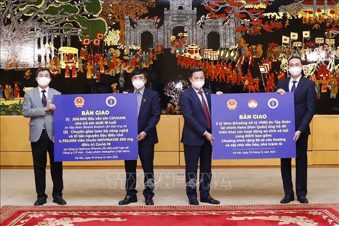 Phó Thủ tướng Lê Minh Khái bàn giao 2 tỷ Won do Tập đoàn Tài chính Hana (Hàn Quốc) ủng hộ cùng với BIDV để triển khai các hoạt động an sinh xã hội cho Phó Chủ tịch Ủy ban Trung ương MTTQ Việt Nam Phùng Khánh Tài và Tổng Thư ký, Chủ nhiệm Văn phòng Quốc hội Bùi Văn Cường bàn giao 200.000 liều vaccine COVAXIN cho trẻ em dưới 18 tuổi do Tập đoàn Bharat Biotech (Ấn Độ) ủng hộ; Chuyển giao toàn bộ công nghệ và 01 tấn nguyên liệu điều chế 4.750.000 viên thuốc MOVINAVIR 200mg điều trị COVID-19 do công ty Optimus Pharma (Ấn Độ) phối hợp với Công ty cổ phần hoá – dược phẩm Mekophar (Việt Nam). Ảnh: Doãn Tấn - TTXVN