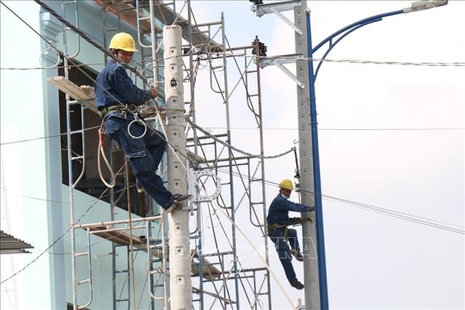 Trong ảnh: Công nhân kéo đường dây diện mới trên tuyến đường Đặng Thúc Vịnh. Ảnh: Tiến Lực – TTXVN