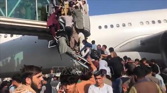 Chỉ vài giờ sau khi lực lượng Taliban tuyên bố kiểm soát thủ đô Kabul của Afghanistan, trong đêm 15/8/2021 rạng sáng 16, hàng nghìn người đổ xô vào đường băng sân bay quốc tế Kabul, cố lao lên các máy bay. Lực lượng Mỹ chịu trách nhiệm đảm bảo an ninh cho sân bay này buộc phải bắn chỉ thiên nhiều lần để cảnh cáo đám đông đã mất kiểm soát. Trong ảnh (trích từ video): Đám đông người sơ tán cố lao lên các máy bay, gây ra cảnh hỗn loạn tại sân bay quốc tế ở Kabul ngày 16/8/2021, khi Taliban tuyên bố kiểm soát Afghanistan. Ảnh: AP/TTXVN
