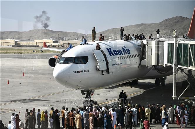 Chỉ vài giờ sau khi lực lượng Taliban tuyên bố kiểm soát thủ đô Kabul của Afghanistan, trong đêm 15/8/2021 rạng sáng 16, hàng nghìn người đổ xô vào đường băng sân bay quốc tế Kabul, cố lao lên các máy bay. Lực lượng Mỹ chịu trách nhiệm đảm bảo an ninh cho sân bay này buộc phải bắn chỉ thiên nhiều lần để cảnh cáo đám đông đã mất kiểm soát. Trong ảnh: Đám đông người sơ tán cố lao lên các máy bay, gây ra cảnh hỗn loạn tại sân bay quốc tế ở Kabul ngày 16/8/2021. Ảnh: AFP/TTXVN