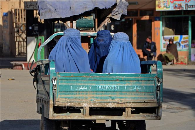 Trong ảnh: Phụ nữ Afghanistan đội khăn trùm đầu khi di chuyển trên đường phố Kandahar, ngày 18/12/2021. Ảnh: AFP/TTXVN