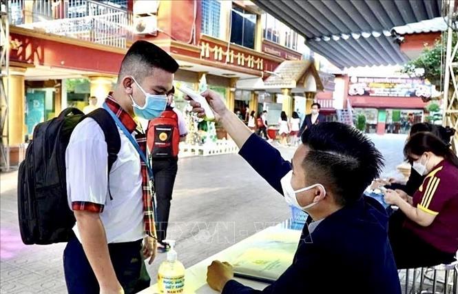 Photo: Students of Nam Viet School at Tan Phu district get temperature check before going into their classes. VNA Photo


