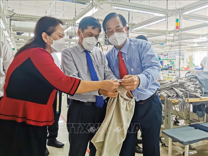 Phó Chủ tịch UBND TP Cần Thơ Nguyễn Văn Hồng (giữa) xem sản phẩm may của Công ty cổ phần May Việt Long Giang. Ảnh: Thanh Liêm - TTXVN