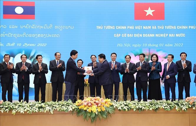 Trong ảnh: Thủ tướng Phạm Minh Chính và Thủ tướng Lào Phankham Viphavanh chứng kiến trao thoả thuận hợp tác đầu tư cho các doanh nghiệp. Ảnh: Dương Giang-TTXVN